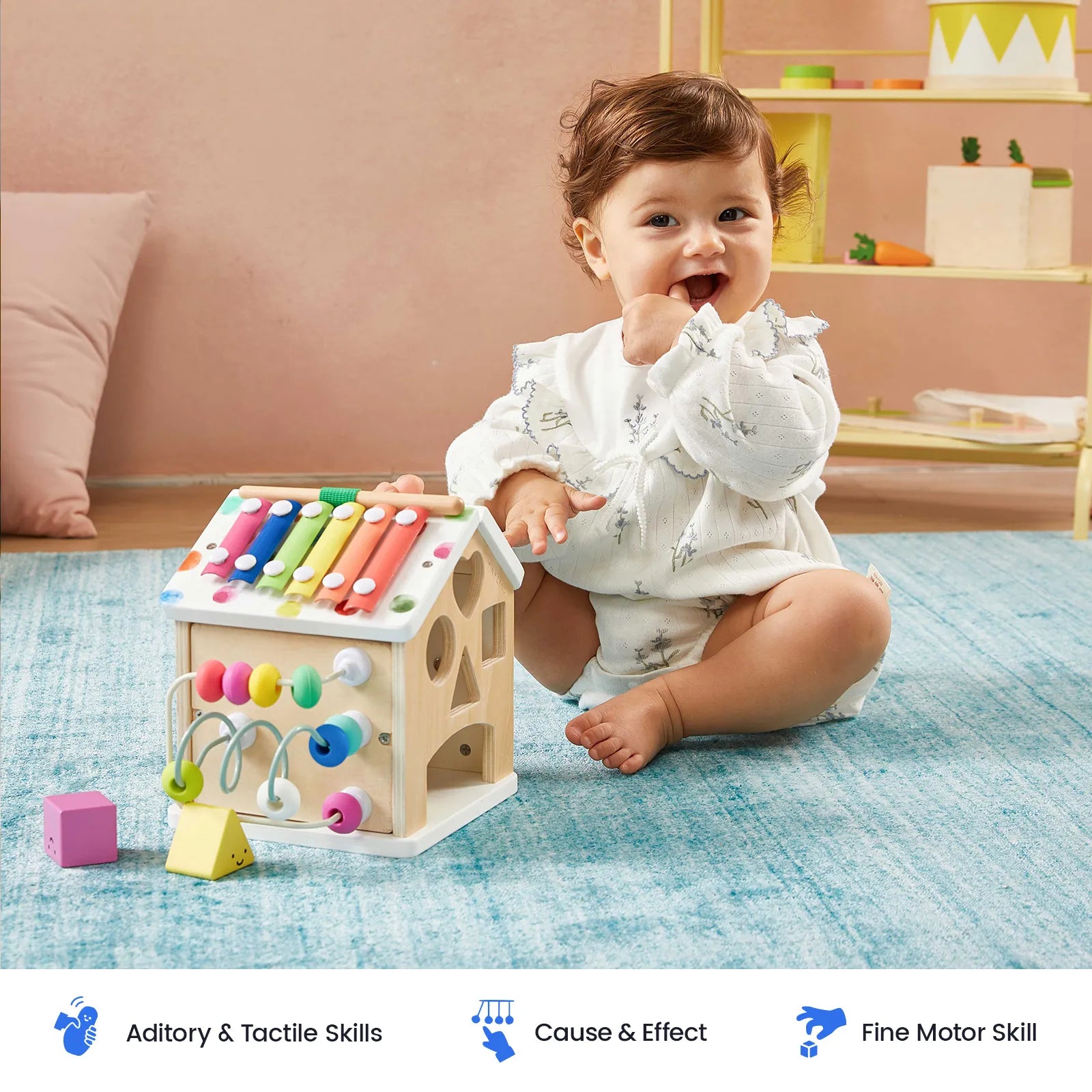 A baby sits on a blue rug, playing with the Tiny Land Rainbow Baby Walker & Activity Cube Developmental Playset, exploring its engaging features. The room is bright with pastel decor. Icons below highlight auditory, tactile, cause and effect, and fine motor skill benefits.