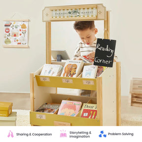 A young child stands at the Tiny Land Farmers’ Market Gift Set: Market Stall & Organic Food Collection, browsing picture books displayed on the wooden stand. The cozy, well-lit classroom is decorated with educational touches and features a role play cash register nearby—perfect for inspiring imaginative shopkeeper games and bringing the kids farmers market toy experience to life.
