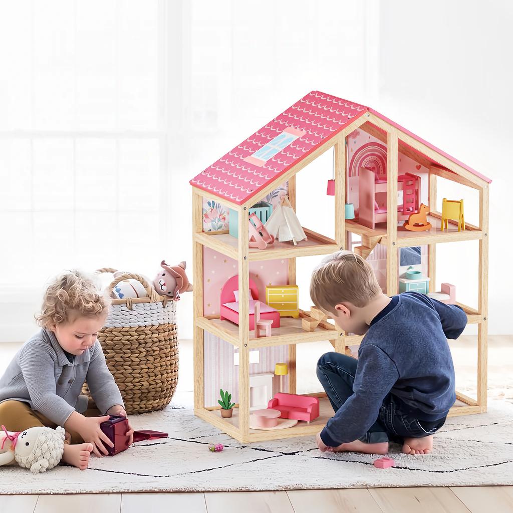 Two young children play on a rug with the Tiny Land® Sweetwood Love Dollhouse without Dolls by Tiny Land. A woven basket of stuffed animals sits nearby, while soft natural light brightens the cozy room.