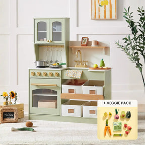 The Tiny Land® Smart Storage Kitchen Harvest Set by Tiny Land features a pastel green wooden play kitchen with utensils, pots, a bowl, baskets, and play food. Shown: toy veggies from the veggie pack. Sunflowers and wall art brighten the background.