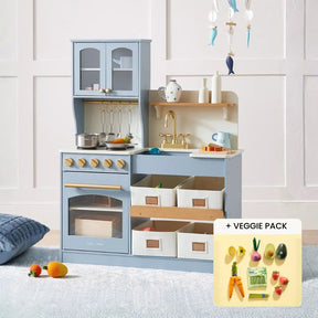 The Tiny Land® Smart Storage Kitchen Harvest Set by Tiny Land is a light blue wooden play kitchen with stovetop, oven, sink, shelves, storage bins, plus pots, utensils, and toy veggies like carrots and avocado—ideal for pretend play.