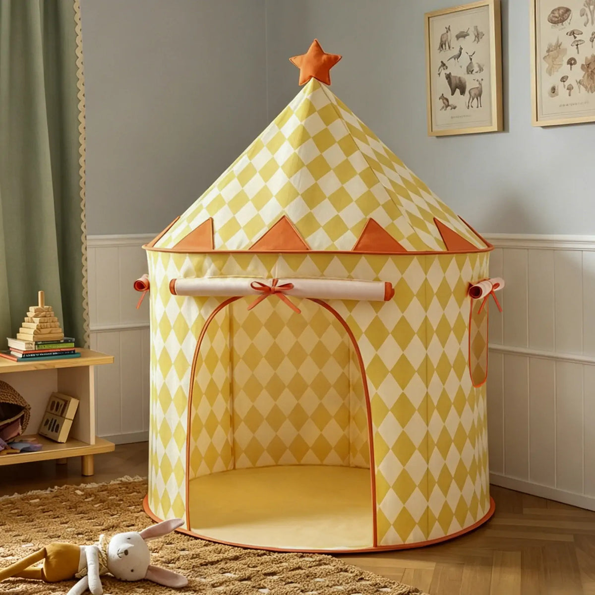 The Tiny Land® Tiny Sunshine Castle Tent by Tiny Land, featuring a yellow and white diamond pattern with orange trim and a star on top, stands in a cozy children’s room with a plush bunny and toys on the wooden floor nearby.