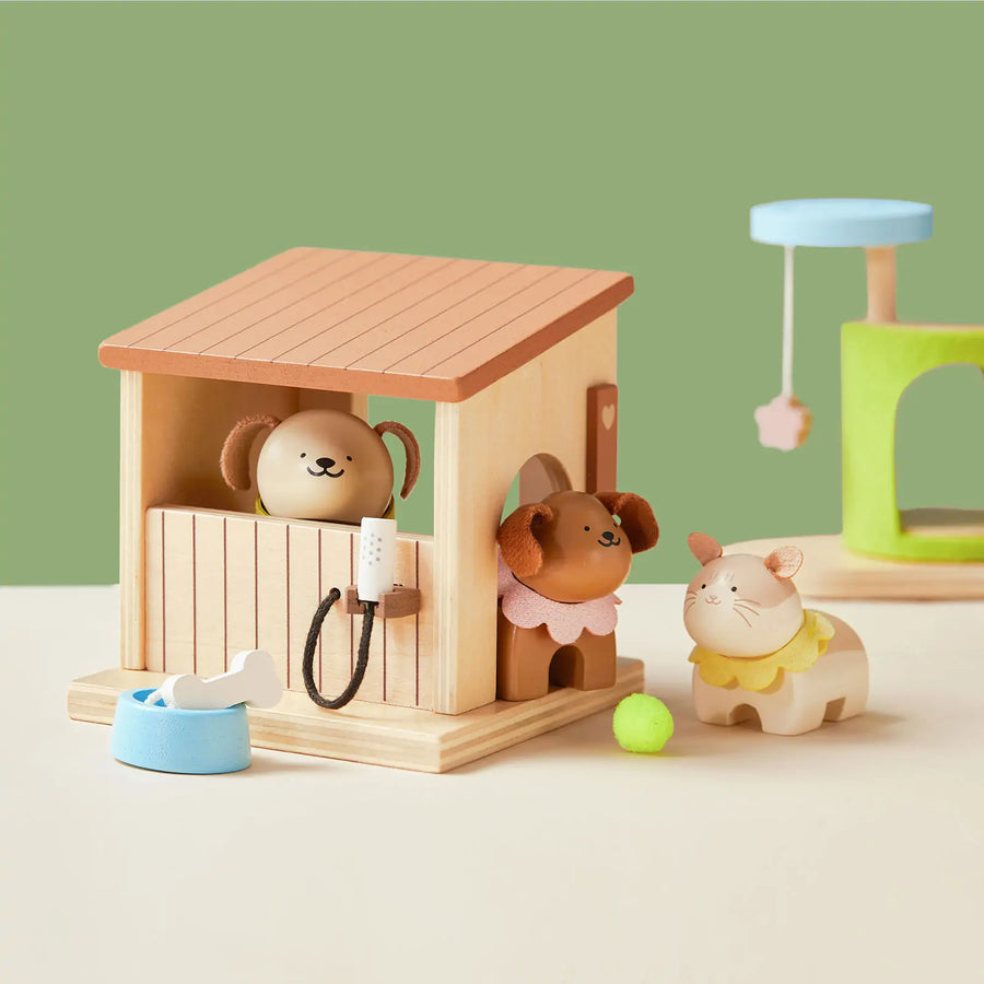 The Tiny Land® Happy Urban Paws play set by Tiny Land creates a mini pet paradise with a toy dog house, smiling dog, brown dog and cat figurines, blue bowl, bone, green ball, and scratching post on a beige base with green backdrop.