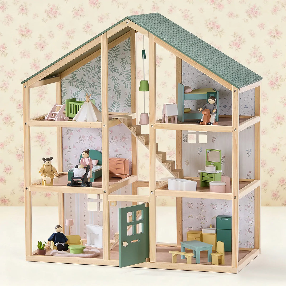 The Tiny Land® Sweetwood Evergreen Dollhouse & Wooden Dollhouse Dolls by Tiny Land INC is a wooden dollhouse with six rooms, miniature furniture, an open front, green roof, floral wallpaper, and four wooden dolls posed in various rooms.