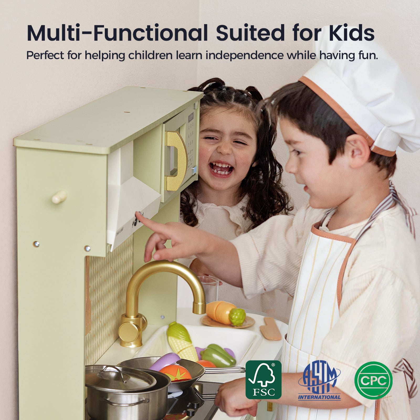 Two young children play with the Tiny Land® PopJoy Play Kitchen in Pink and Green, pretending to cook using plastic food and utensils. The text above highlights how this play kitchen from Tiny Land encourages learning independence. Certification logos appear at the bottom.|Sage