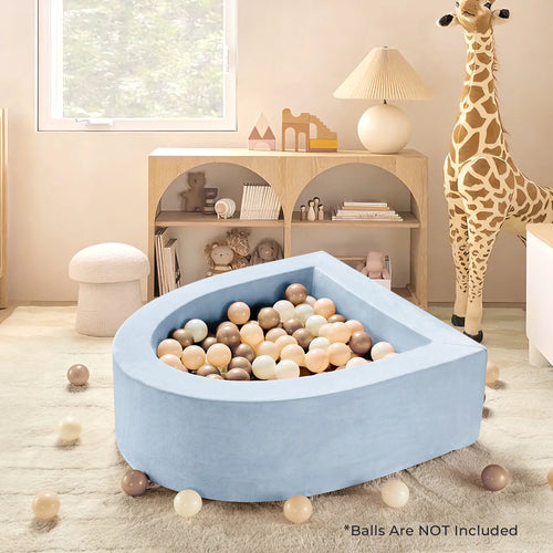 A children’s room features the Tiny Land® PlayNest Soft Foam Ball Pit by Tiny Land—an inviting, blue teardrop-shaped pit (balls not included) ideal for sensory play. The scene includes a large plush giraffe, light wood shelves, and pastel balls filling the ball pit and scattered on the carpet. Text on image: Balls are NOT included.|Blue
