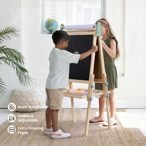 Two children, a boy and a girl, draw on the Tiny Land® 3-in-1 Art Easel for Kids - Morandi in a bright room. This double-sided easel by Tiny Land features a blackboard, paper roll, shelf, and icons showing its multifunctionality and extra drawing paper.