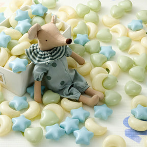 A fabric mouse doll in blue sits beside a box of Tiny Land® Fun-Shapes Ocean Ball (200 pcs) by Tiny Land, featuring yellow heart and blue star non-toxic play balls scattered across a light surface.