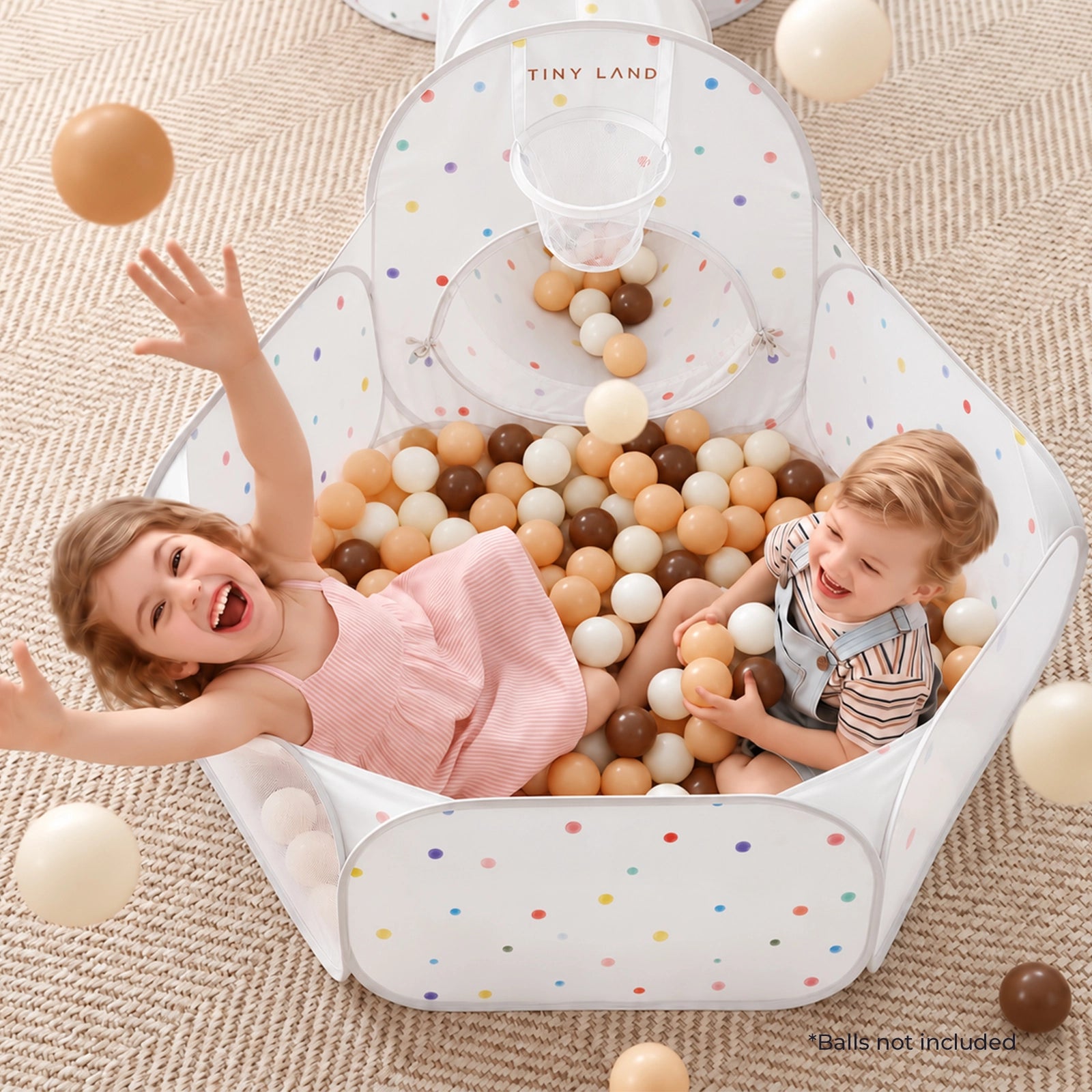 Two children laugh inside a Tiny Land® Compact Adventure 3-in-1 Play Tunnel with a built-in basketball hoop, surrounded by a sea of scattered plastic balls from the ball pit.|Colorful Dots