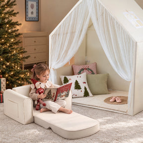 A young girl sits on a Tiny Land Cozy Nook Bundle – Kids Tent with Star Lights & GentleSnug Chair reading a book next to a cozy play nook with sheer curtains.|Mesh