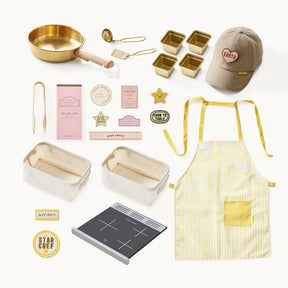 Here’s the revised sentence using your product data: A flat lay featuring items from the Tiny Land® BistroSwitch Kitchen & Fridge Set by Tiny Land—including a gold frying pan, utensils, loaf pans, badges, a cap, apron, recipe cards, cooking labels, an induction cooktop, and a yellow-striped apron—perfectly arranged on a white background for imaginative kids’ play kitchens and pretend play.