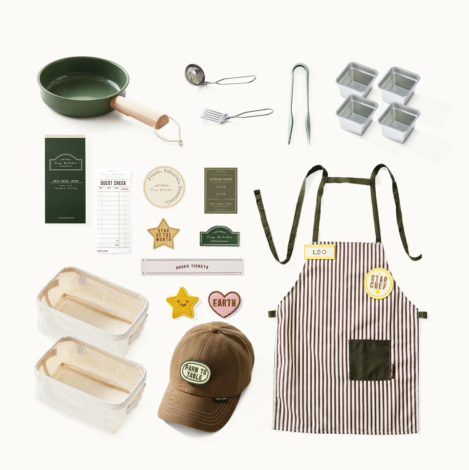 A flat lay of the Tiny Land® BistroSwitch Play Kitchen by Tiny Land features a green pan, whisk, tongs, loaf and square pans, a striped apron, brown hat, order slips, and badges—perfect for pretend play or sparking creativity.|Green