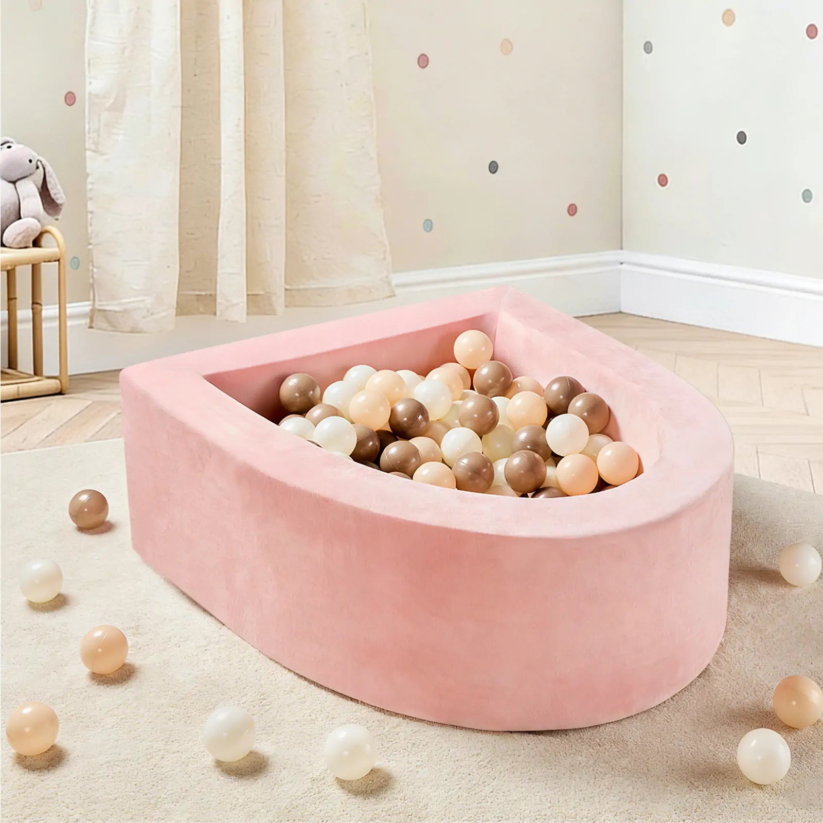 The Early Bird Eggs-Tiny Land® PlayNest Ball Pit with 200 Ocean Balls by Tiny Land INC sits in a child’s room with light wood flooring, polka dot walls, and a curtain, with some pastel ocean balls scattered nearby and a plush toy in the background.|pink
