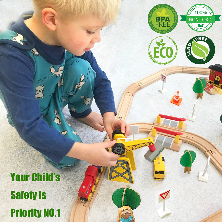 A young child in blue pajamas plays with the Tiny Land® Wooden Track Trains 55 Pcs on the floor. Text reads, “Your Child’s Safety is Priority NO. 1.” Green eco-friendly and safety icons from Tiny Land appear in the top right corner.|55 Pcs