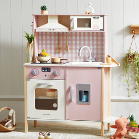 The Tiny Land® PopJoy Play Kitchen in Pink/Green by Tiny Land is a wooden toy kitchen set that includes features such as an oven, stove, sink, microwave, fridge, and utensils, all accented by a charming checkered backsplash. Surrounded by plush toys and plants, it creates a cozy and inviting pretend play scene in the playroom.|Pink