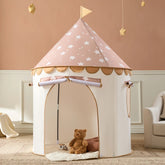 The Tiny Land® Kids Tent from Target features a pink and white star-patterned roof, scalloped trim, and a flag. Inside this indoor toddler tent, a teddy bear rests on a comfy mat amid soft decor and light walls.