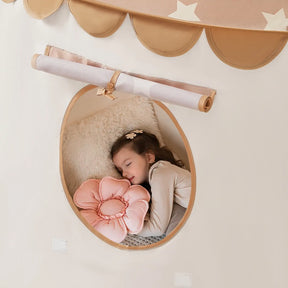 A young girl sleeps peacefully in the Tiny Land® Cheerful Pennant Castle Tent by Tiny Land, hugging a pink flower-shaped pillow and resting on a fluffy white cushion, looking cozy and content in her charming playhouse.