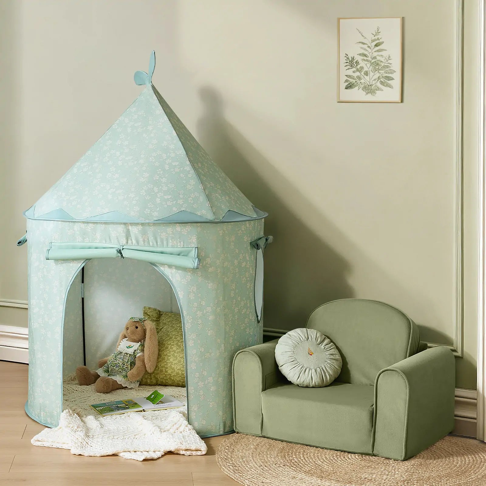 A cozy kids' play area features the Tiny Land® Tiny Sprout Castle Tent—with a stuffed rabbit and pillow inside—set beside a green armchair on a round woven rug, and accented with a botanical picture on the wall.