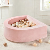 The Tiny Land® PlayNest Ball Pit with 200 Ocean Balls by Tiny Land INC, in soft pink crescent-shaped foam, is set on a plush white rug in a bright modern room with white walls and a window.|Pink