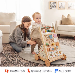 A toddler pushes the Tiny Land® Versatile Natural Wooden Baby Walker while a woman supports them in a cozy living room. Skill icons for gross motor, balance & coordination, and fine motor are displayed at the bottom.
