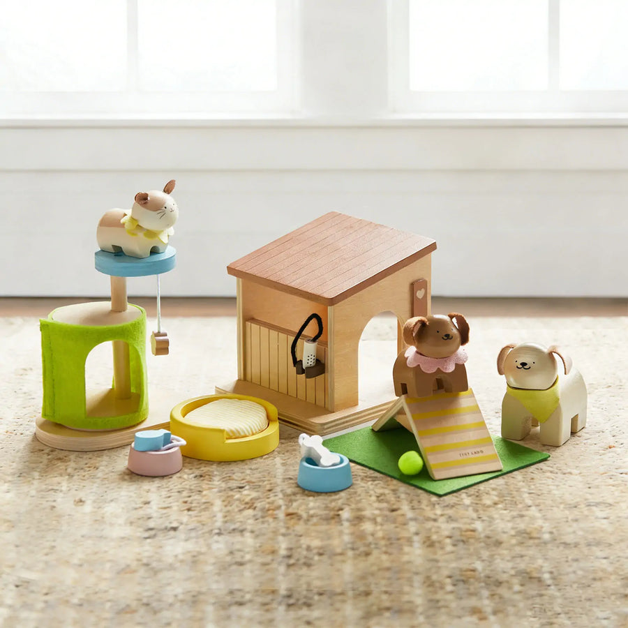 The Tiny Land® Happy Urban Paws set by Tiny Land is a wooden pretend play kit with a cat on a tower, two dogs by a doghouse, and accessories like bowls, tent, mat, ball, and brush—all on a soft carpeted base.