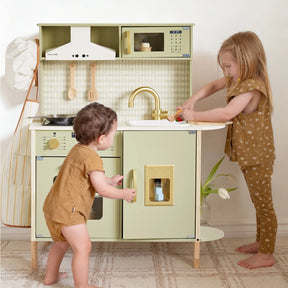 Two young children play with the Tiny Land® PopJoy Play Kitchen - Green. The older child pretends to wash vegetables at the sink, while the younger opens the oven. Both wear brown outfits and stand on a patterned rug. Brand: Tiny Land.