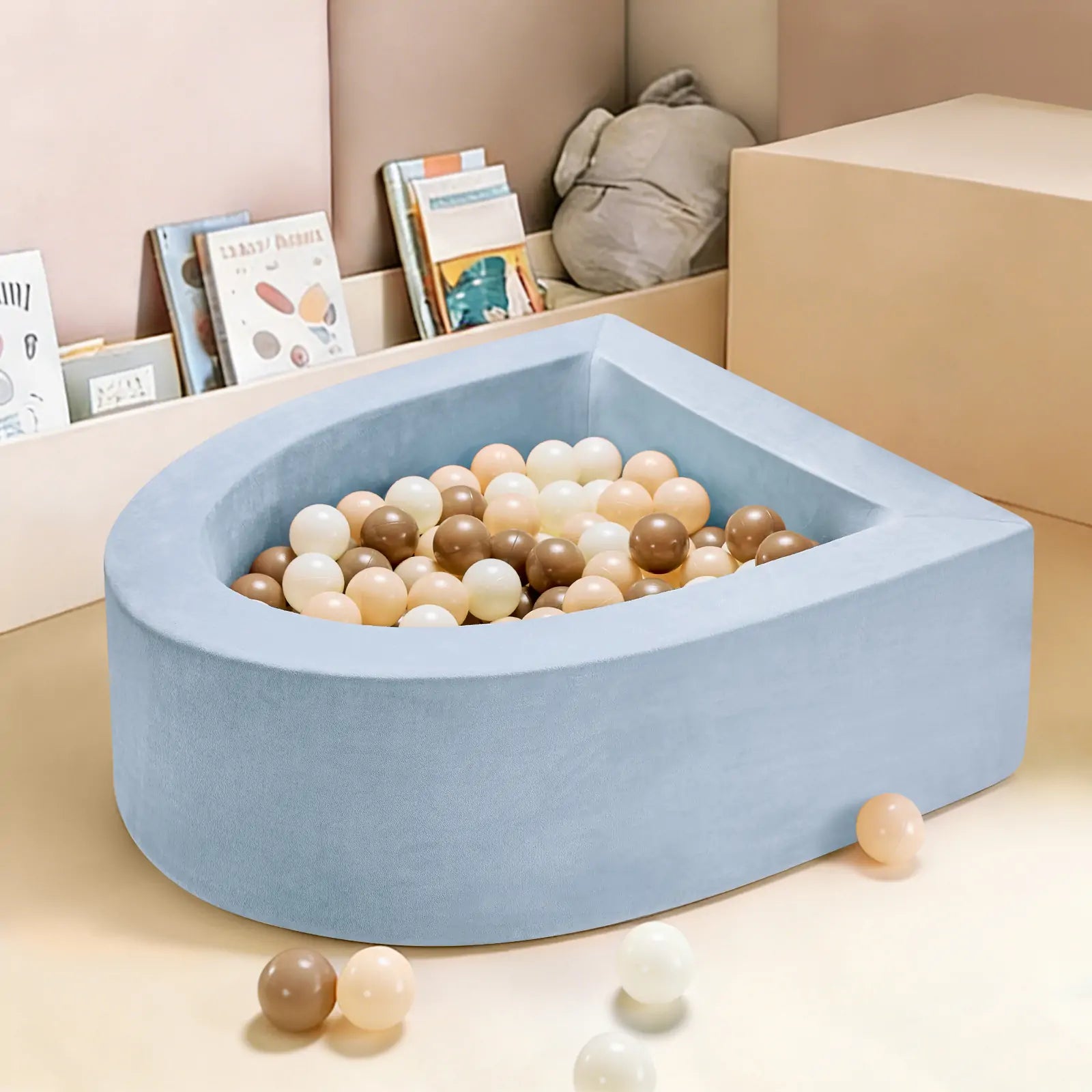 The Tiny Land® Blue PlayNest Ball Pit with 200 beige, cream, and brown ocean balls by Tiny Land INC sits in a playroom with light-colored walls, children's books, a stuffed toy, and some scattered balls on the floor.|blue