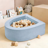 The Tiny Land® Blue PlayNest Ball Pit with 200 beige, cream, and brown ocean balls by Tiny Land INC sits in a playroom with light-colored walls, children's books, a stuffed toy, and some scattered balls on the floor.|blue