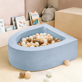 The Tiny Land® Blue PlayNest Ball Pit with 200 beige, cream, and brown ocean balls by Tiny Land INC sits in a playroom with light-colored walls, children's books, a stuffed toy, and some scattered balls on the floor.|blue