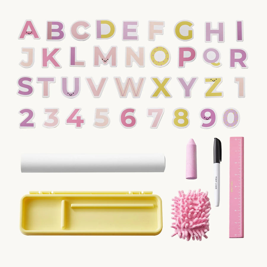 The Tiny Land® Double-Sided Magnetic Tabletop Easel by Tiny Land is displayed on a white background with alphabet and number magnets, a pink ruler, pink chalk, a black marker, a pink eraser, a yellow storage box, and a white roll—perfect accessories for an art station or magnetic whiteboard setup.|Pink