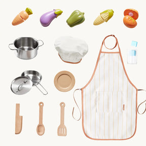 The Tiny Land® PopJoy Play Kitchen includes wooden utensils, metal pots and pans, a chef’s hat, apron, toy vegetables, a plate, a straw cup, and a light brown toy knife—perfect for pretend play by Tiny Land.