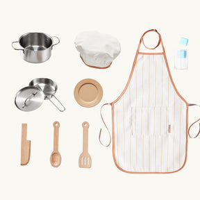 The Tiny Land® PopJoy Play Kitchen - Green by Tiny Land features a striped apron, chef hat, metal pot and pan with lids, plate, cup, wooden utensils, and knife—all arranged neatly on a white background.