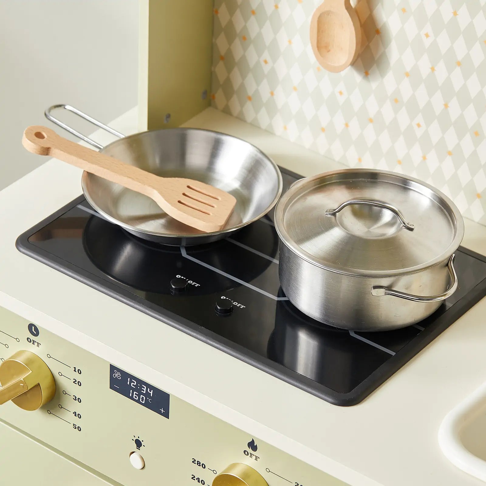 The Tiny Land® PopJoy Play Kitchen - Green features a metal frying pan, wooden spatula, lidded pot, gold knobs, digital display, and patterned backsplash—perfect for pretend cooking fun from Tiny Land.