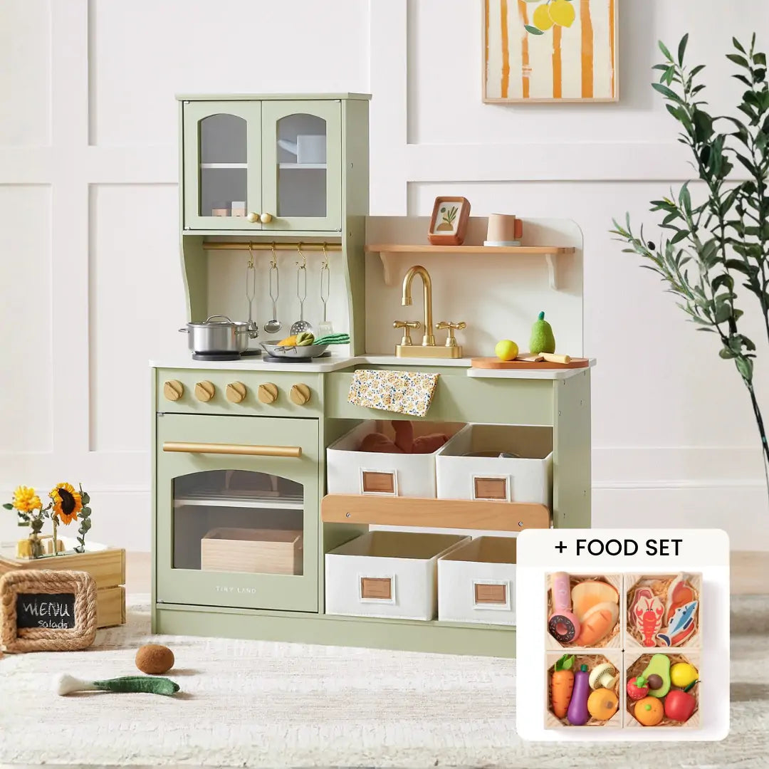 The Tiny Land® Serenity Wooden Kitchen & Wooden Food Set by Tiny Land features a pastel green play kitchen with a stove, oven, sink, and shelves, plus toy utensils, pots, baskets, wooden food pieces, and a small set of toy fruits and veggies.