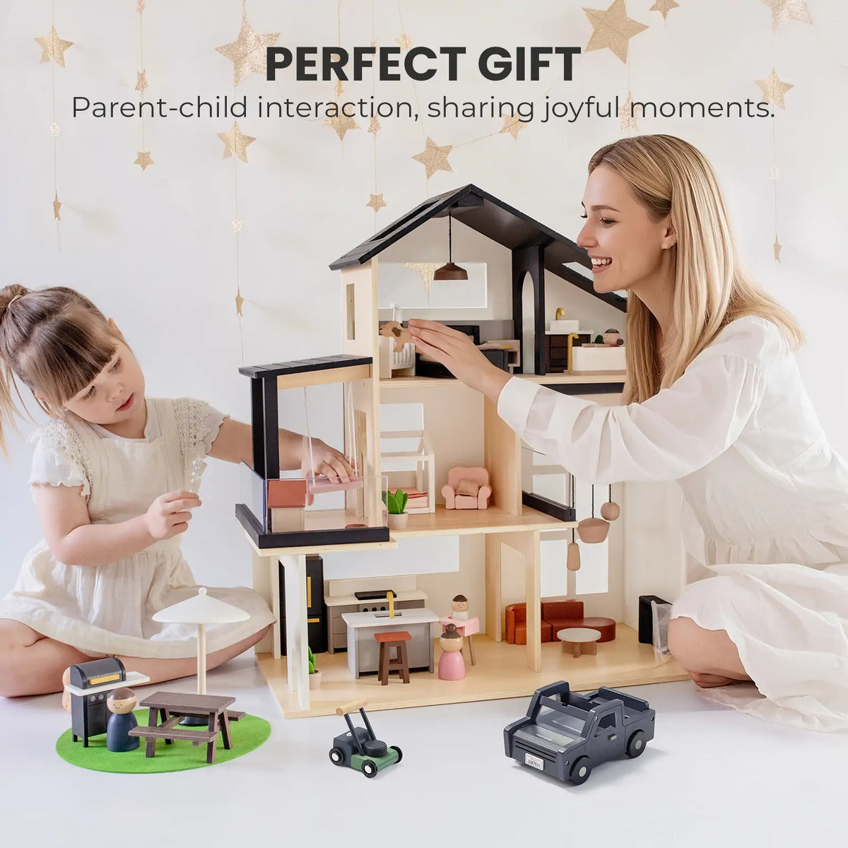 A woman and young girl enjoy imaginative play with the Tiny Land Sweet Family Gift Set—Black Dollhouse, Garage, and Extra Dolls—in a bright room with hanging stars. Text above: Perfect Gift for parent-child bonding and shared joy.