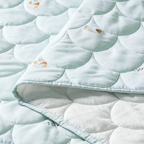 A folded Tiny Land® Sweet Woodland Kids Play Tent quilt by Tiny Land INC is shown close-up, featuring a light blue scalloped stitched pattern, colorful butterfly designs, and a white dotted underside—perfect for cozy woodland play.