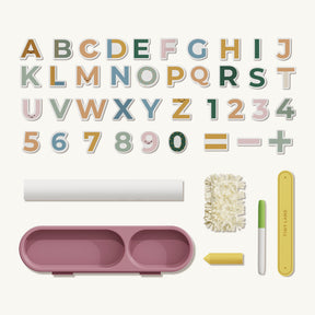 Tiny Land® Double-Sided Magnetic Tabletop Easel - Yellow by Tiny Land comes with pastel A–Z letters, 1–9 numbers, and math symbols, arranged above accessories like a brush, chalk, marker, eraser, and a pink holder with two compartments.