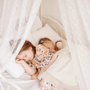 Two young children sleeping peacefully under the sheer white canopy of a Tiny Land Cozy Nook Bundle in a cozy play nook.|Mesh
