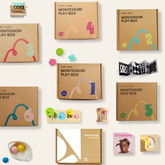 Flat lay of Tiny Land® Montessori Complete Baby Set (0-24 Months) by Tiny Land, featuring brown boxes, colorful toys, rainbow stacker, wooden rattles, felt balls, picture cards, and sensory play items for motor skill development on a beige background.