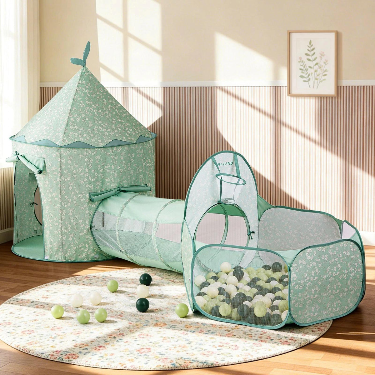 The Tiny Land® Green Adventure 3-in-1 Play Tunnel & Fun-Shapes Ocean Ball Set by Tiny Land INC features a mint green play tent, sensory tunnel, and ball pit with green, white, and black balls on a rug in a softly lit room with striped wallpaper and leaf art.