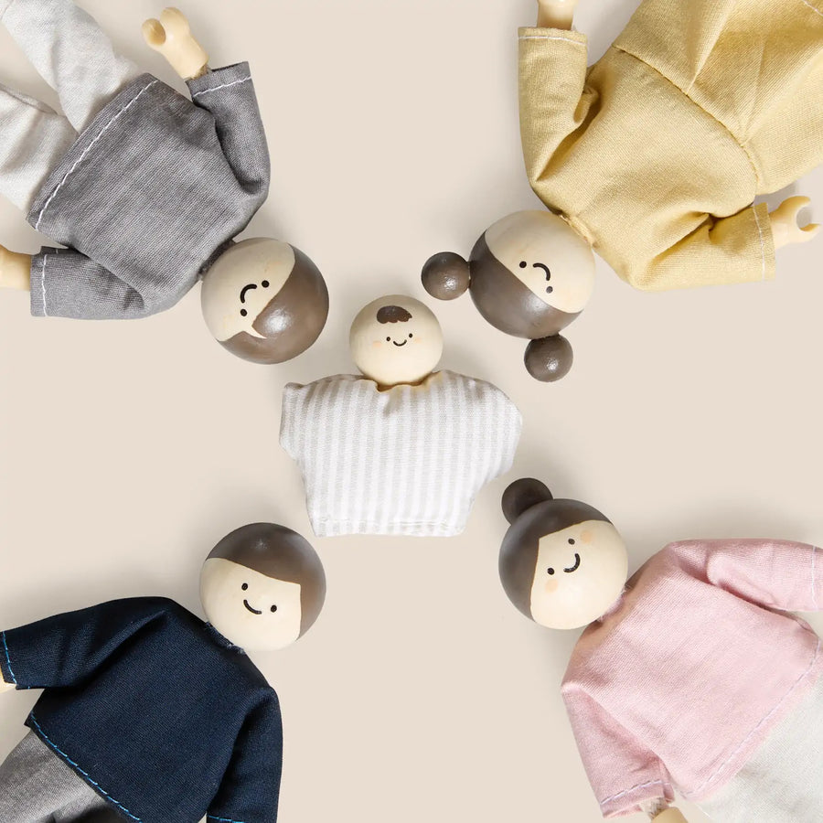 Five Tiny Land® Wooden Dollhouse Dolls by Tiny Land, featuring simple painted faces and colorful clothing, are arranged in a circle on a beige background with their heads pointing toward the center.