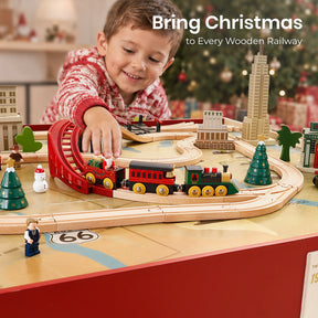 A child plays with a Tiny Land® Christmas Express Wooden Train Accessory Set on a decorated table, featuring a red holiday-themed engine, buildings, evergreen trees, and a snowman figure.