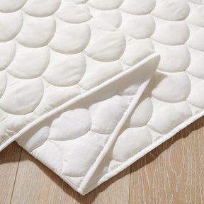 Off-white quilted fabric pad from the Tiny Land® Cozy Nook – GentleSnug Chair & Playhouse Tent with a scalloped pattern, partially folded on a light wood floor, perfect for a kids reading nook.|White