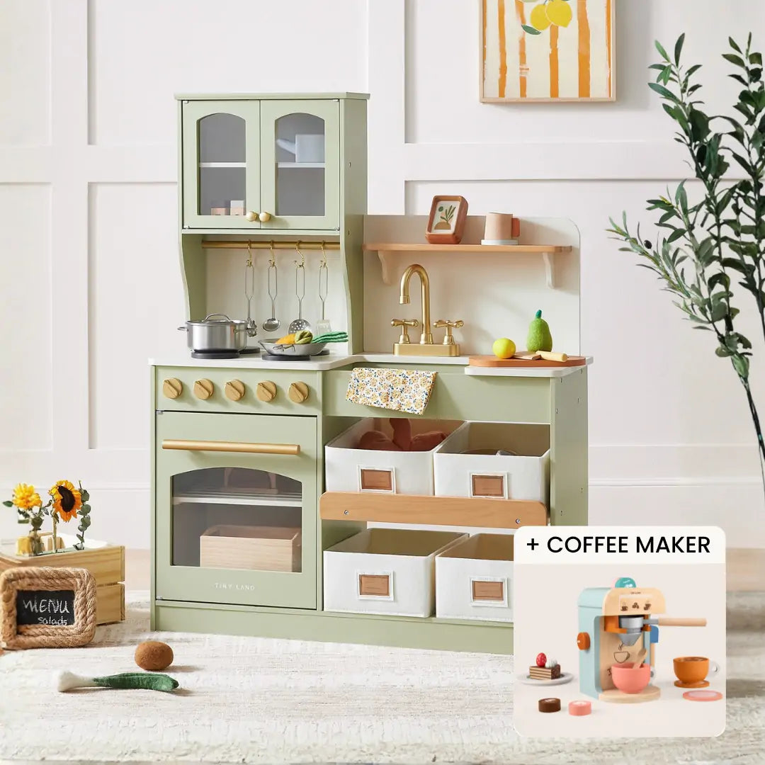 The Tiny Land® Serenity Wooden Kitchen & Coffee Maker by Tiny Land features a pastel green wooden kitchen set with cabinets, stove, sink, storage bins, play food, utensils, and an inset of the coffee maker playset with cups. Flowers and wall decor are seen behind.