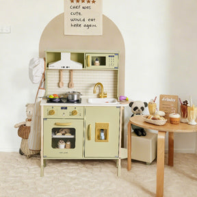 A delightful scene features the Tiny Land® PopJoy Play Kitchen in Pink / Green by Tiny Land, a wooden toy kitchen set adorned with play pots, pans, and pretend food. Beside it stands a small table displaying make-believe drinks and desserts, while plush stuffed animals assemble for lively pretend play. A whimsical sign on the wall proclaims: THE CHEF WAS CUTE. would eat here again.|Sage
