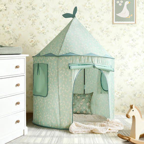 The Tiny Land® Tiny Sprout Castle Tent in mint green, featuring a pointed roof and leaf accents, stands in a child’s room with floral wallpaper, near a wooden rocking horse, white dresser, and framed goose picture on the wall.