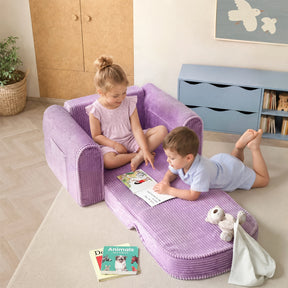 Two young children read a book together on a lavender fold-out sofa in a cozy room. Nearby are more books, a stuffed bunny, and a blanket on the floor, along with the Tiny Land® GentleSnug Corduroy Kid Chair—a comfy kids lounger by Tiny Land perfect for quiet story time.|Purple