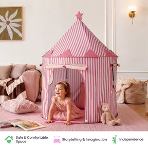 A toddler in a pink dress and tiara smiles as she crawls out of a Tiny Land® Kids Tent – Indoor Tent for Toddlers in a cozy room decorated with a teddy bear, soft rug, and pastel accents. Text icons highlight safety, imagination, and independence from Tiny Land.|PInk