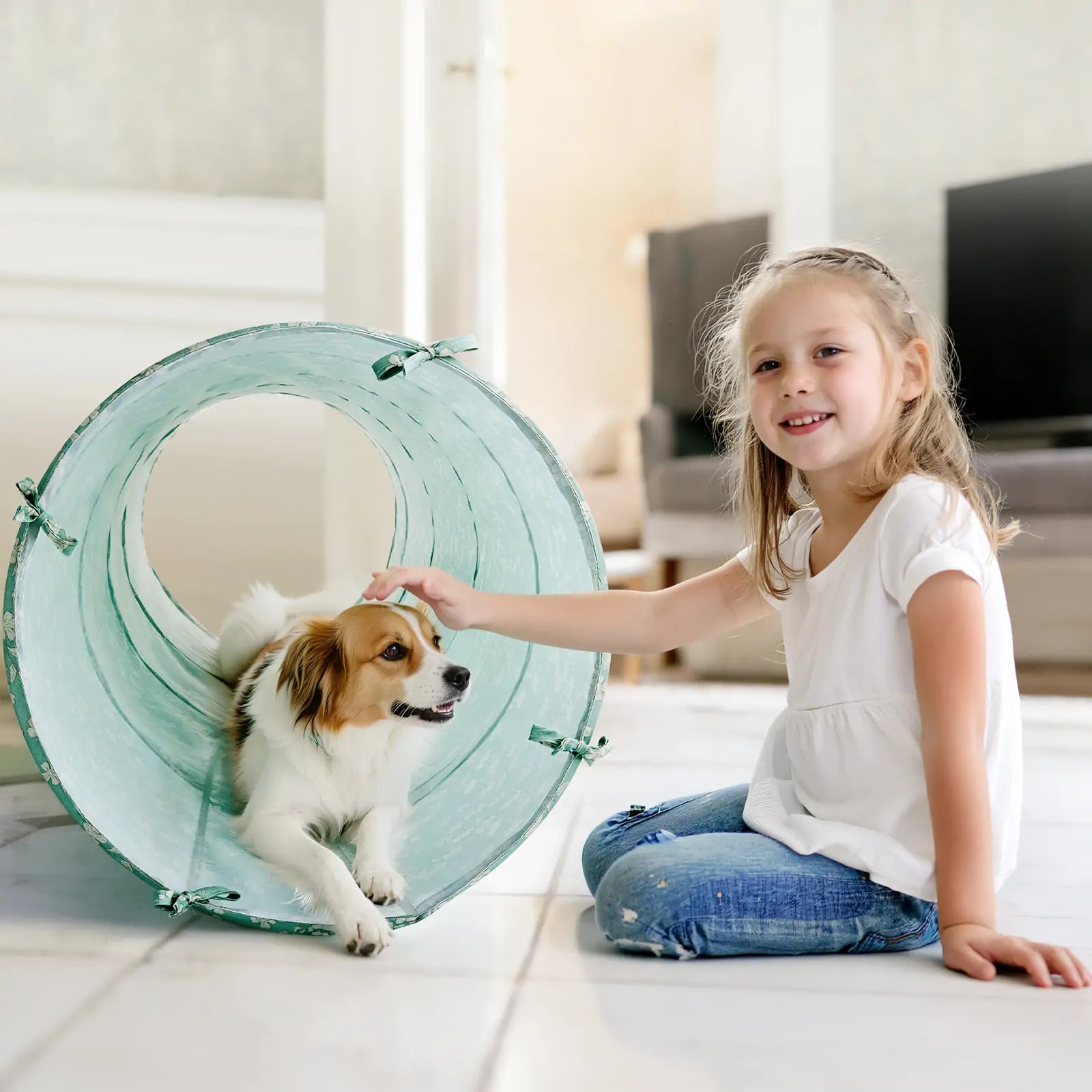 A young girl smiles as she pets a small dog peeking out from the Tiny Land® Adventure Play Tunnel - Green by Tiny Land in a bright, modern living room.|green