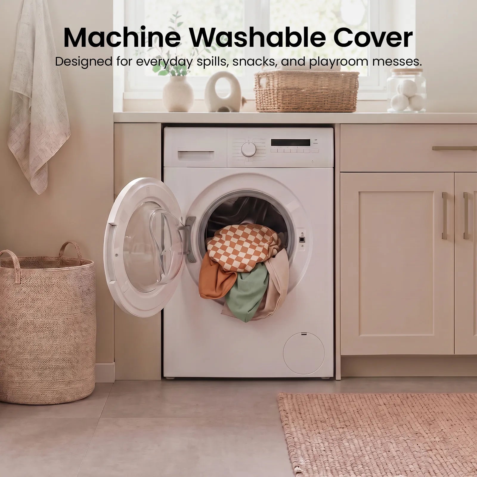 A washing machine with its door open, filled with colorful fabric—including pieces from the Tiny Land® PlayNest Climbing Blocks by Tiny Land. The room features beige cabinets, a woven basket, and a towel hanging on the wall. Text above reads Machine Washable Cover.
